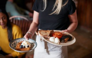 A server carrying breakfast dishes at a restaurant in Naples, FL.