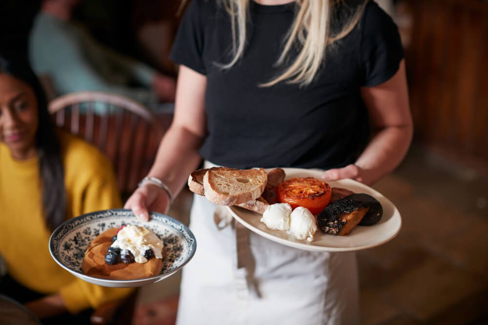 A server carrying breakfast dishes at a restaurant in Naples, FL.