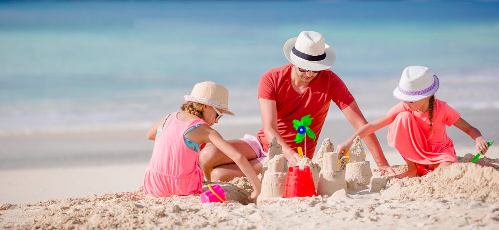A family making a sandcastle on the beach during spring break in Naples, Florida.