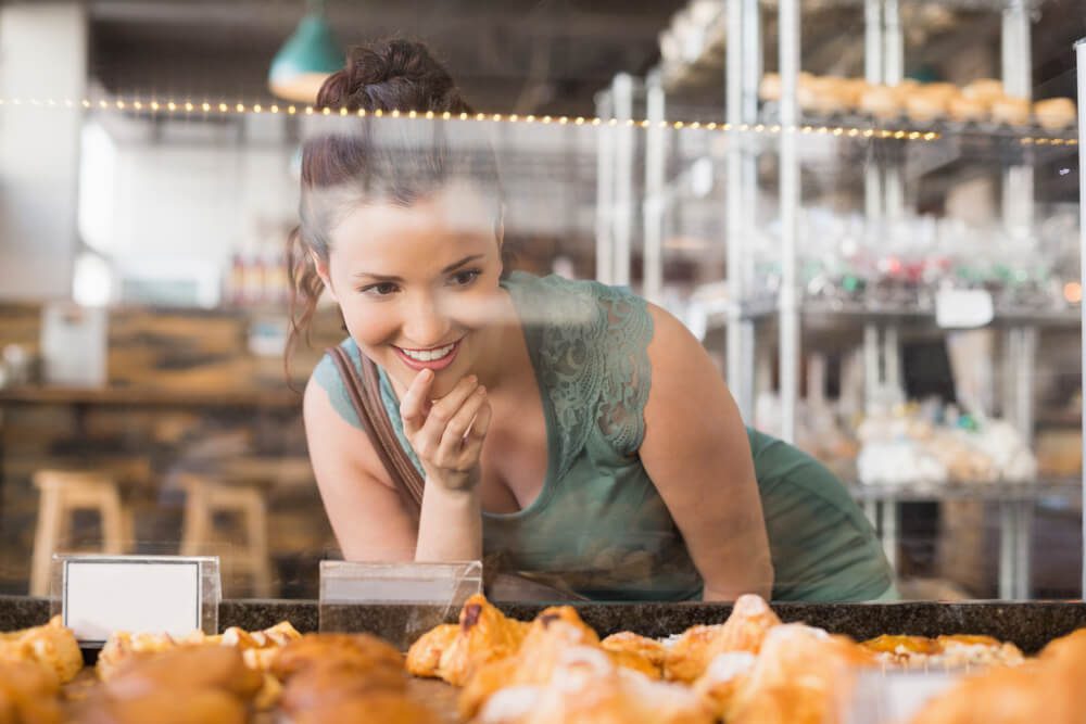 A woman looking at the display case in a bakery in Naples, FL.